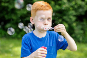 Young-red-headed-boy-child-blows-bubbles-on-a-summer-day